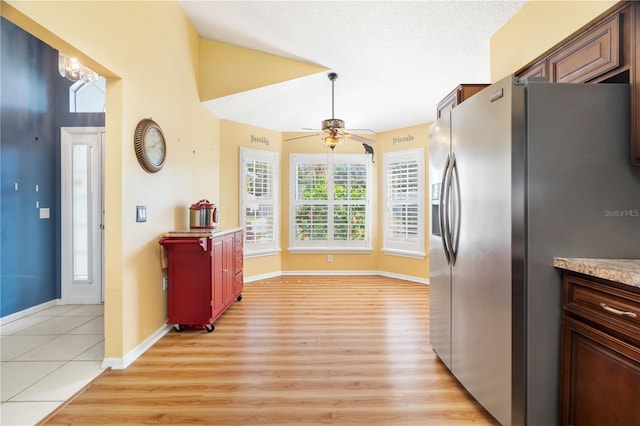 kitchen with ceiling fan, light wood-type flooring, stainless steel fridge with ice dispenser, and a textured ceiling