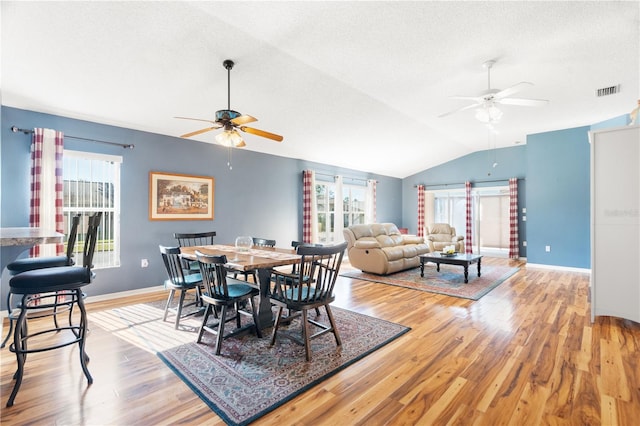 dining space with wood-type flooring, a textured ceiling, vaulted ceiling, and ceiling fan