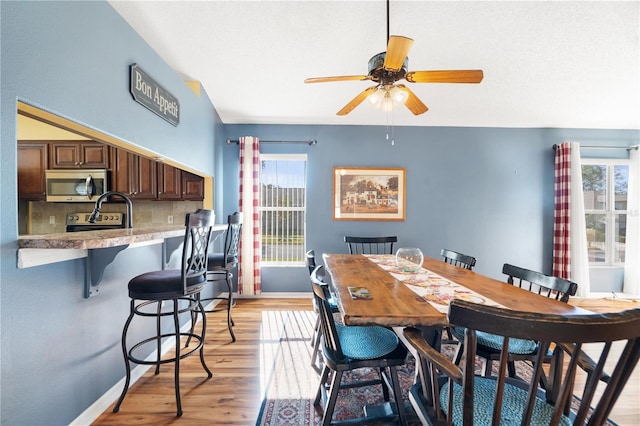 dining room with light wood-type flooring, a wealth of natural light, and ceiling fan