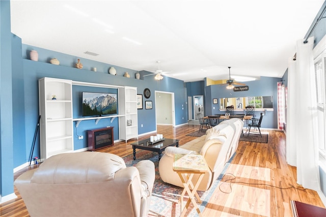 living room with ceiling fan, lofted ceiling, and light wood-type flooring