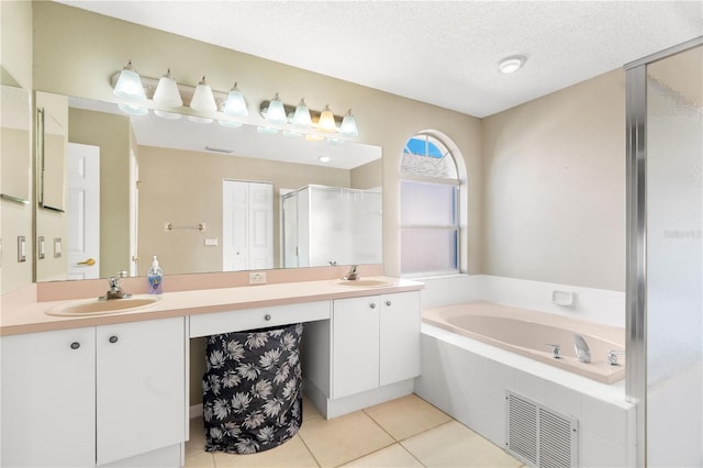 bathroom with tile patterned flooring, vanity, independent shower and bath, and a textured ceiling