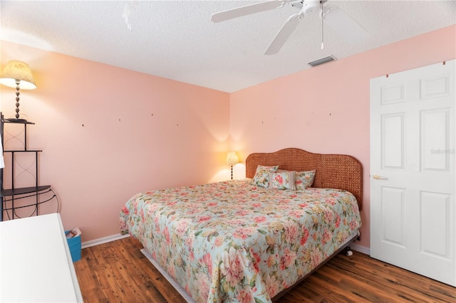 bedroom with ceiling fan, dark hardwood / wood-style floors, and a textured ceiling