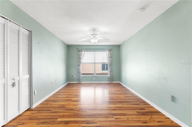 unfurnished bedroom featuring hardwood / wood-style flooring, ceiling fan, a textured ceiling, and a closet