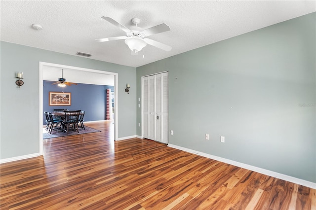 unfurnished room with ceiling fan, hardwood / wood-style floors, and a textured ceiling