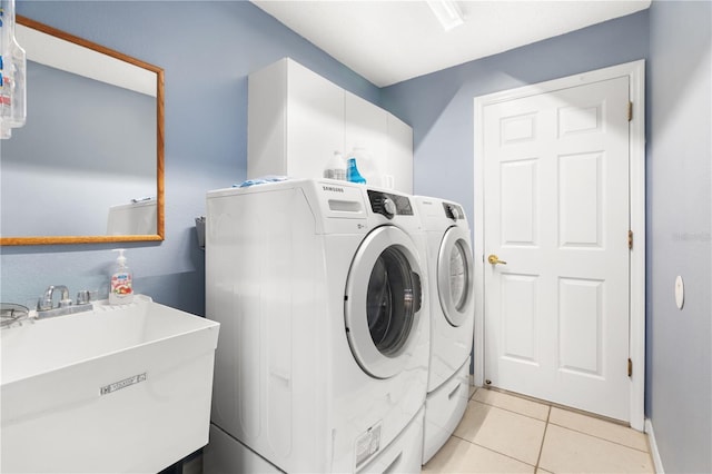 laundry area featuring light tile patterned floors, washer and clothes dryer, and sink