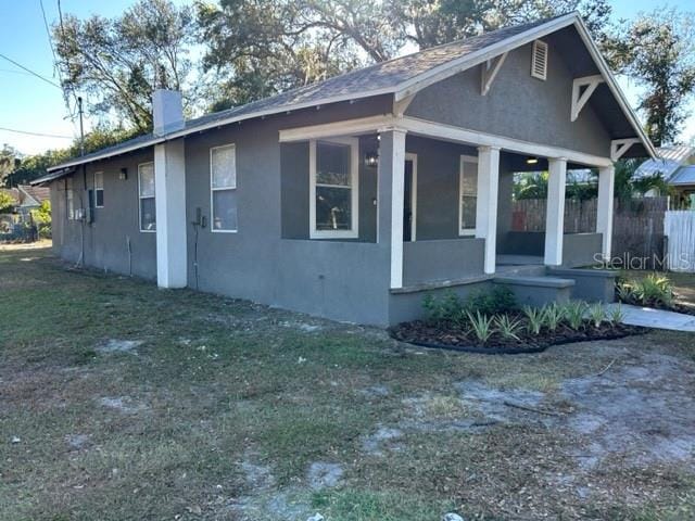 view of property exterior with covered porch and a yard