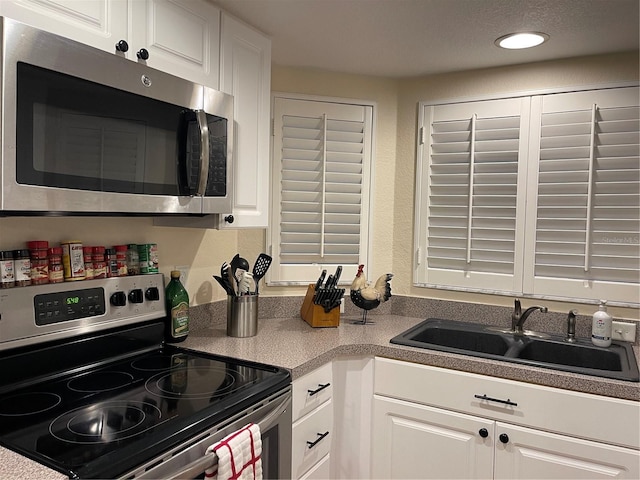 kitchen featuring stainless steel appliances, sink, and white cabinets