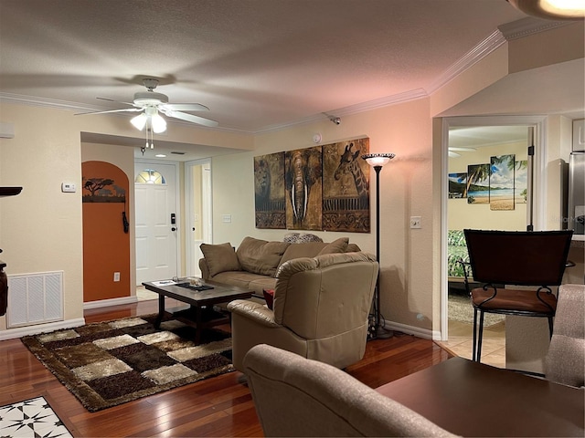 living room featuring ornamental molding, dark wood-type flooring, a textured ceiling, and ceiling fan