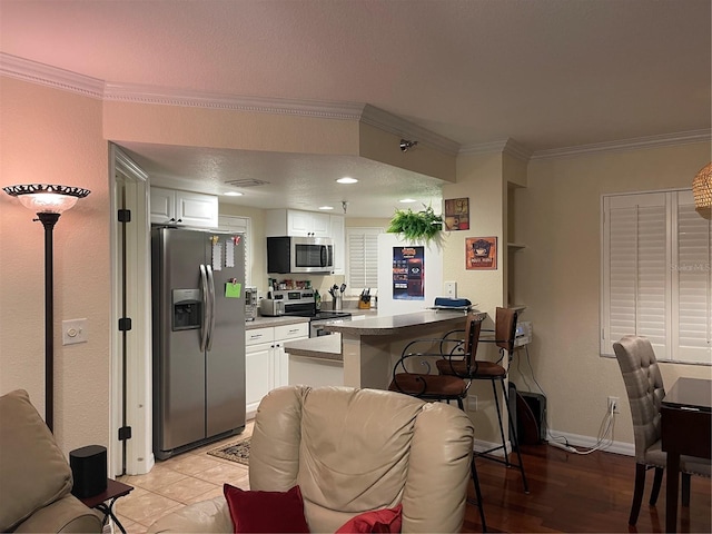 kitchen with white cabinetry, crown molding, kitchen peninsula, and appliances with stainless steel finishes