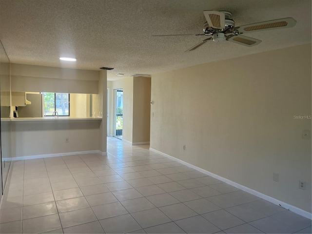 tiled empty room with ceiling fan, sink, and a textured ceiling