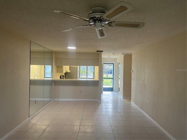 spare room with ceiling fan, light tile patterned flooring, and a textured ceiling