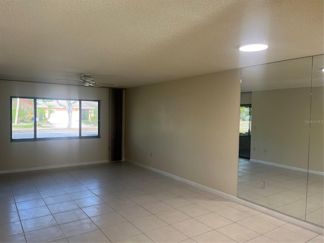 tiled spare room featuring a textured ceiling and ceiling fan