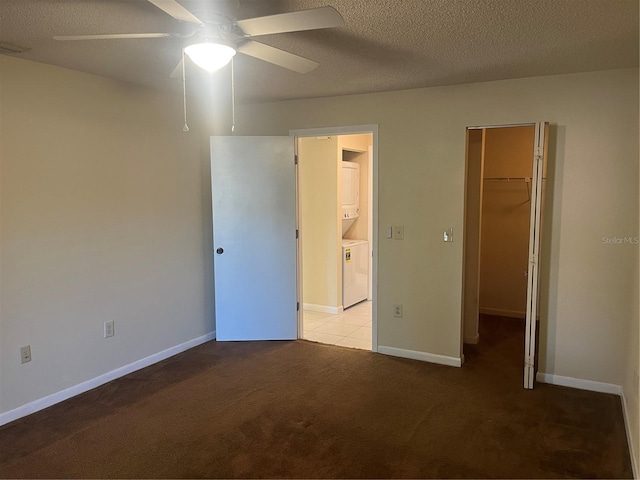 unfurnished bedroom with light carpet, stacked washing maching and dryer, ceiling fan, a spacious closet, and a closet