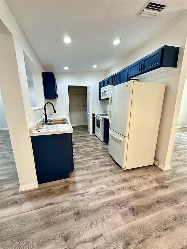 kitchen featuring light wood-type flooring, white appliances, blue cabinets, and sink