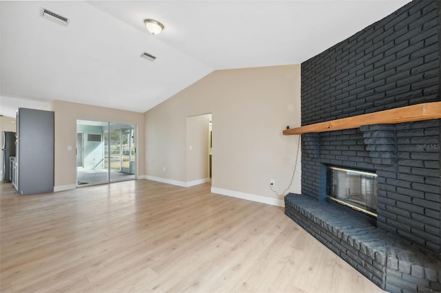 living room featuring vaulted ceiling, a fireplace, and light hardwood / wood-style flooring