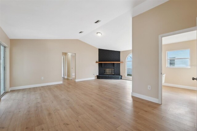 unfurnished living room featuring light hardwood / wood-style floors, vaulted ceiling, and plenty of natural light