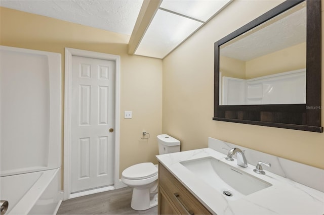 bathroom with wood-type flooring, vanity, a textured ceiling, and toilet