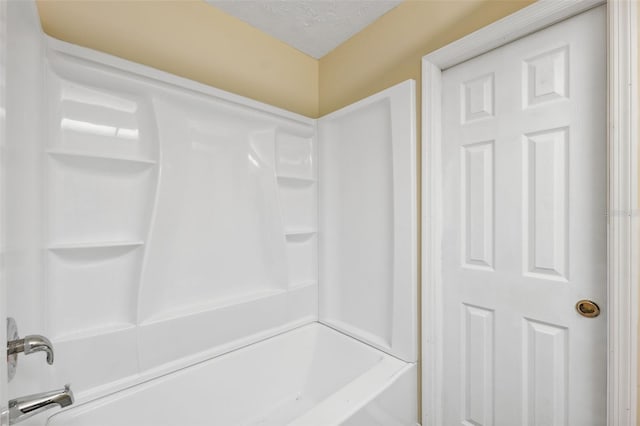 bathroom featuring bathtub / shower combination and a textured ceiling