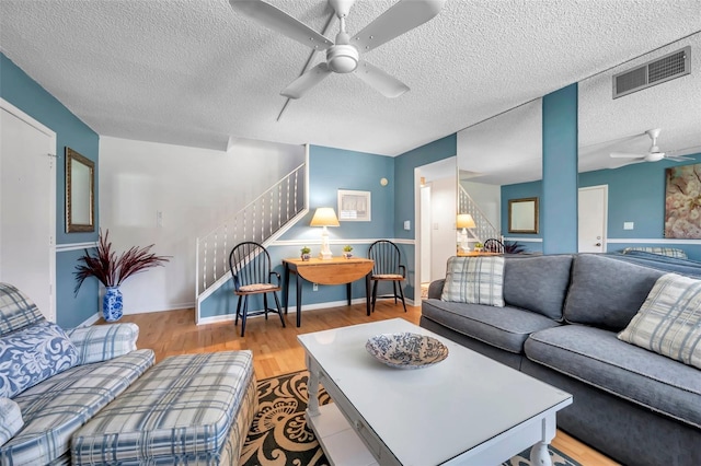 living room featuring ceiling fan, a textured ceiling, and light wood-type flooring