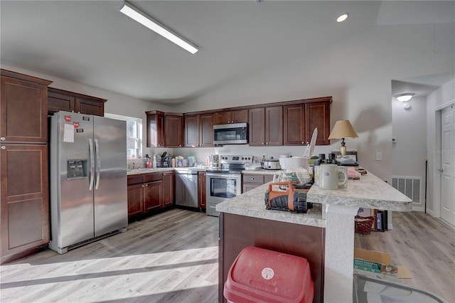 kitchen featuring dark brown cabinetry, stainless steel appliances, a kitchen breakfast bar, light hardwood / wood-style floors, and vaulted ceiling
