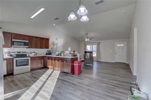 kitchen featuring appliances with stainless steel finishes, ceiling fan with notable chandelier, light hardwood / wood-style floors, hanging light fixtures, and lofted ceiling