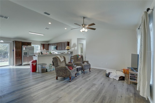 living room featuring light hardwood / wood-style floors, vaulted ceiling, and ceiling fan
