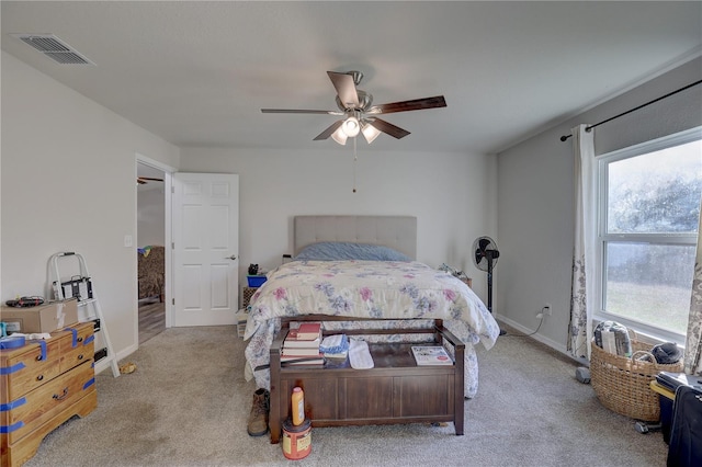 bedroom with ceiling fan, light colored carpet, and multiple windows