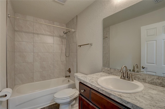 full bathroom with toilet, vanity, a textured ceiling, and tiled shower / bath