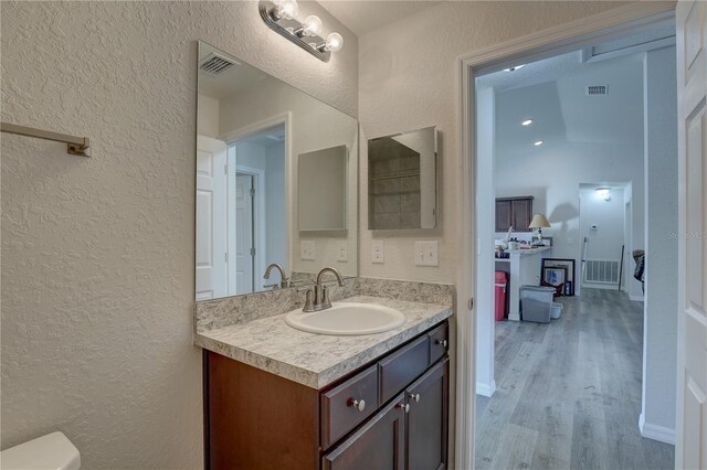 bathroom featuring hardwood / wood-style floors, vanity, and lofted ceiling