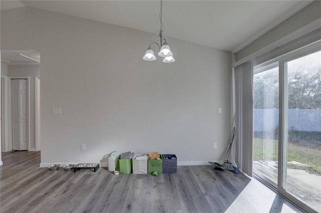 spare room with an inviting chandelier, light wood-type flooring, and vaulted ceiling