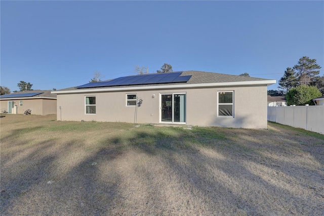 back of property with a lawn and solar panels