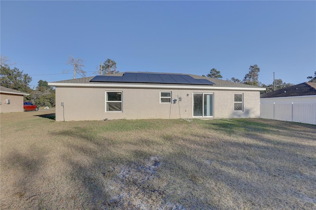 back of house featuring a lawn and solar panels