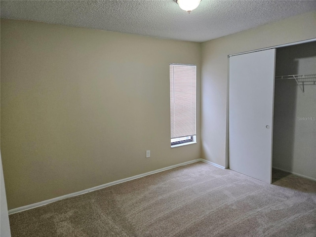 unfurnished bedroom with carpet, a textured ceiling, and a closet