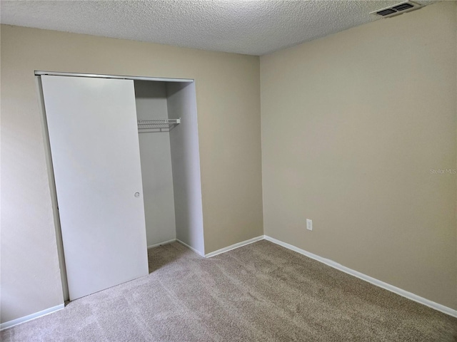 unfurnished bedroom featuring a closet, light colored carpet, and a textured ceiling