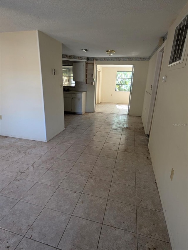 tiled empty room with a textured ceiling