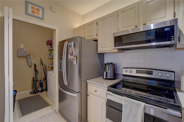 kitchen featuring appliances with stainless steel finishes, backsplash, washer / clothes dryer, and light tile patterned floors