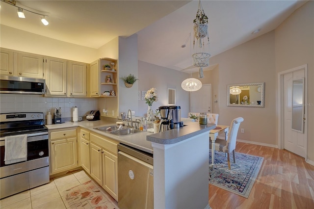 kitchen featuring kitchen peninsula, appliances with stainless steel finishes, hanging light fixtures, and sink