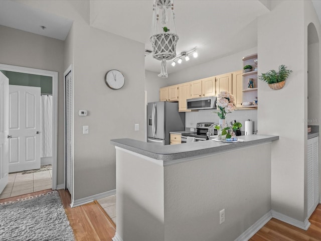 kitchen with light wood-style flooring, light brown cabinets, stainless steel appliances, and decorative backsplash