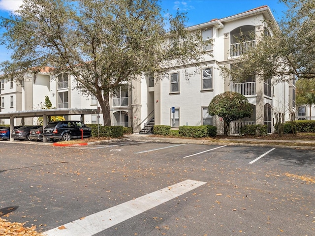 view of building exterior with covered and uncovered parking