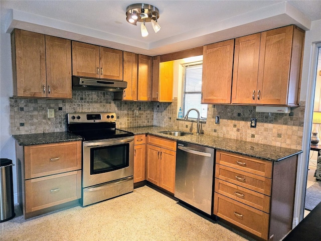 kitchen featuring stainless steel appliances, sink, dark stone countertops, and backsplash