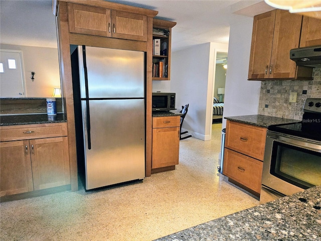 kitchen with dark stone countertops, decorative backsplash, and appliances with stainless steel finishes