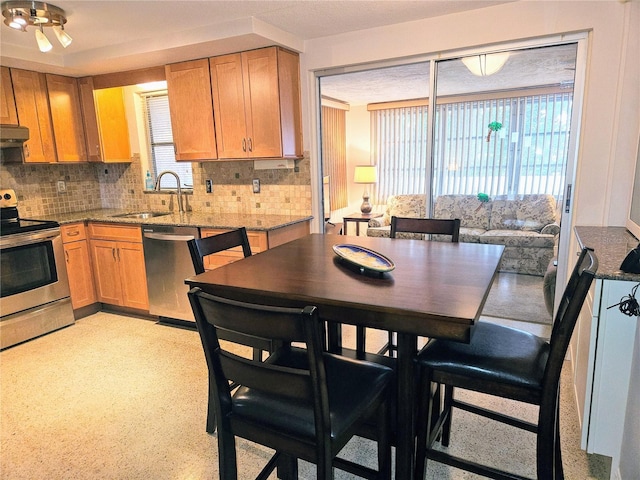 kitchen with sink, backsplash, stainless steel appliances, and light stone countertops