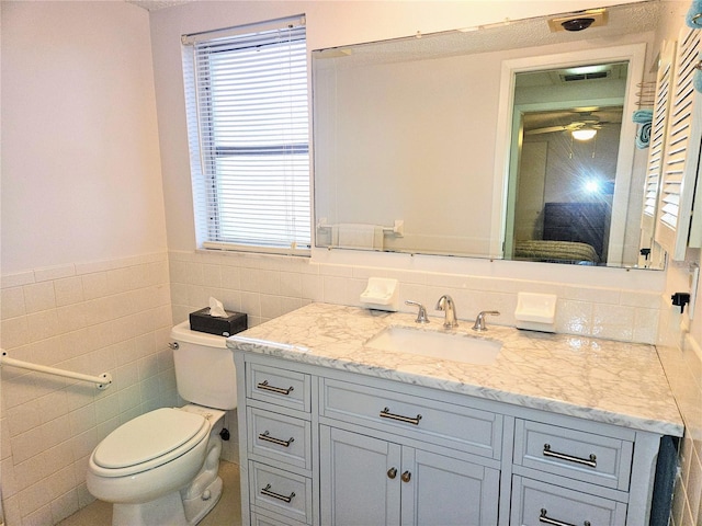 bathroom with vanity, tile walls, ceiling fan, and toilet