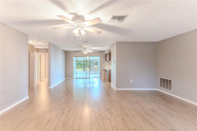 empty room featuring ceiling fan, a textured ceiling, and light wood-type flooring