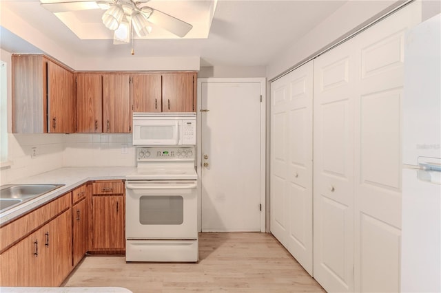 kitchen with ceiling fan, sink, tasteful backsplash, light hardwood / wood-style floors, and white appliances