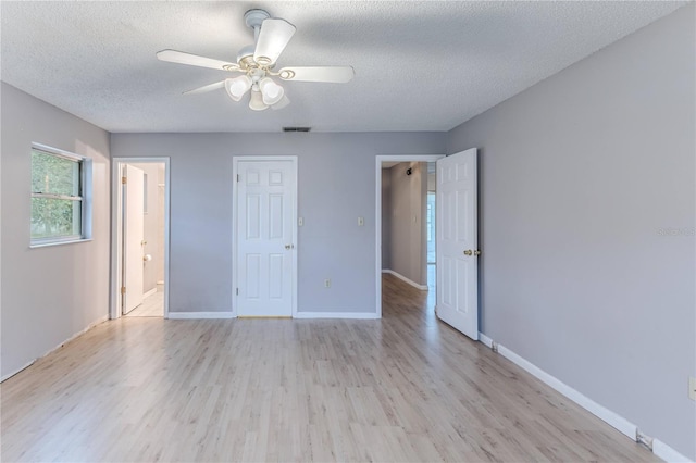 unfurnished bedroom with ensuite bath, ceiling fan, light hardwood / wood-style floors, and a textured ceiling