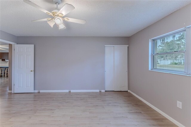 unfurnished bedroom featuring a closet, ceiling fan, light hardwood / wood-style flooring, and a textured ceiling