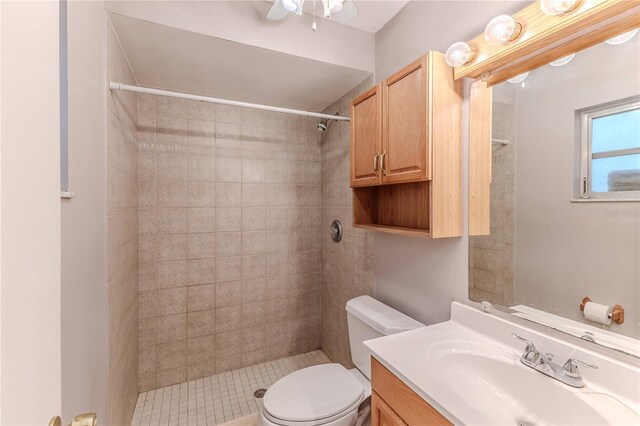 bathroom featuring a tile shower, ceiling fan, vanity, and toilet