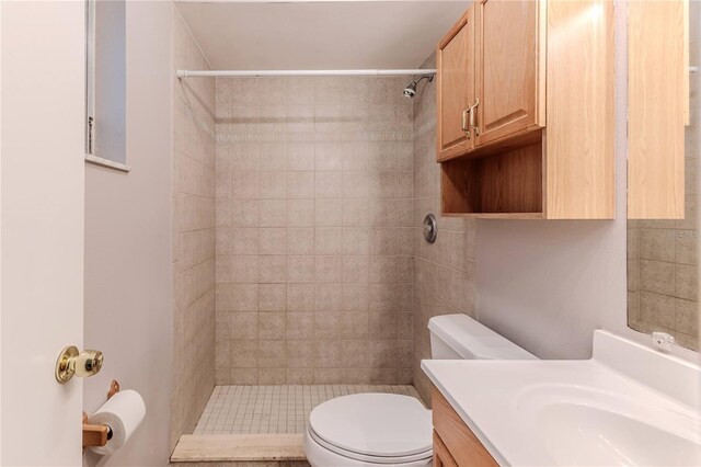 bathroom with tiled shower, vanity, and toilet