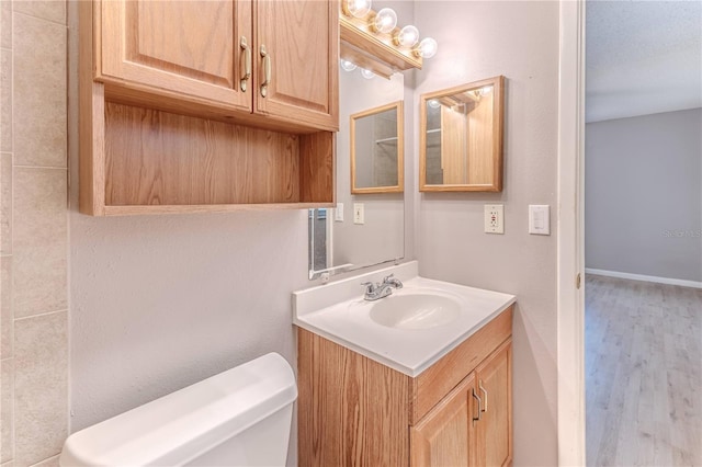 bathroom featuring a textured ceiling, vanity, hardwood / wood-style flooring, and toilet